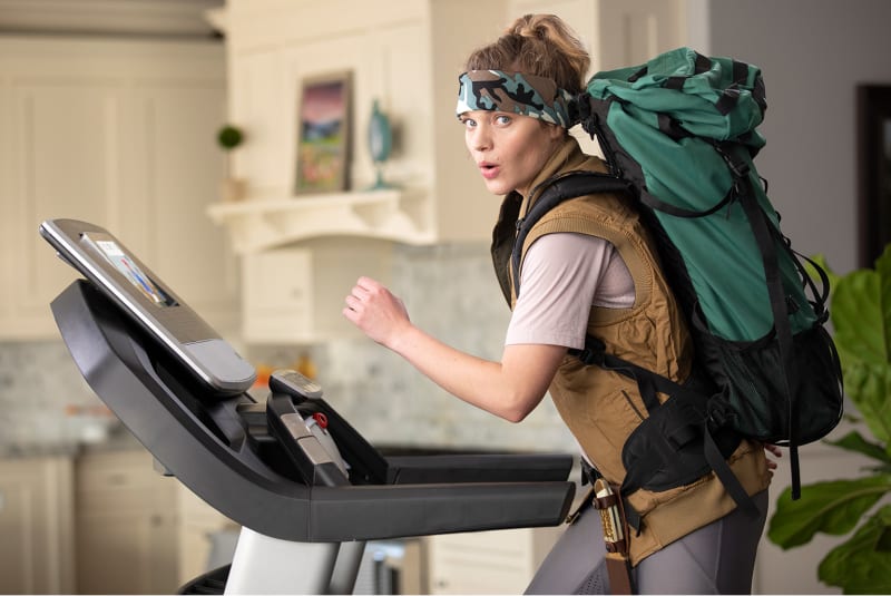 Woman walking on a treadmill while wearing hiking gear.