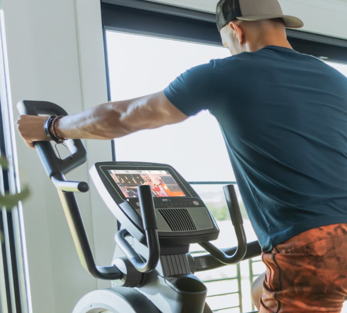Man working out with an iFIT trainer on the Carbon HIIT H10.